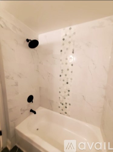 A white bathtub with a shower head and a shower head attached to the wall.
