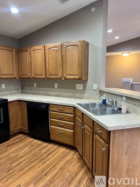 A kitchen with wooden cabinets and a black dishwasher.