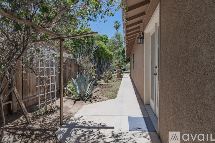 A sunny day in a residential area with a house and a fence.