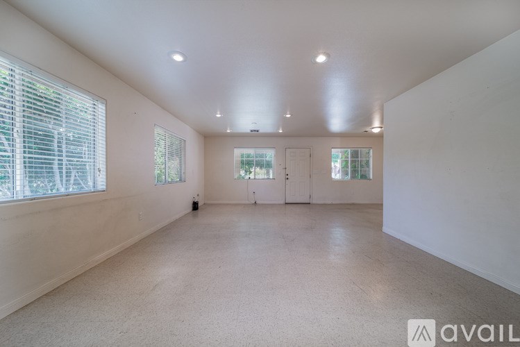 A spacious room with white walls and carpeted floor.