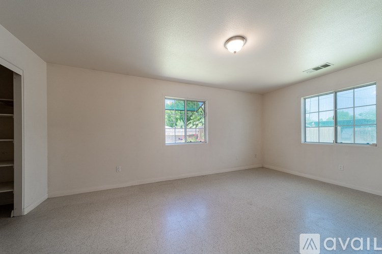 A spacious empty room with a window and a door.