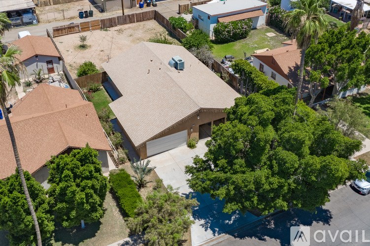 A house with a brown roof is surrounded by trees and a driveway.
