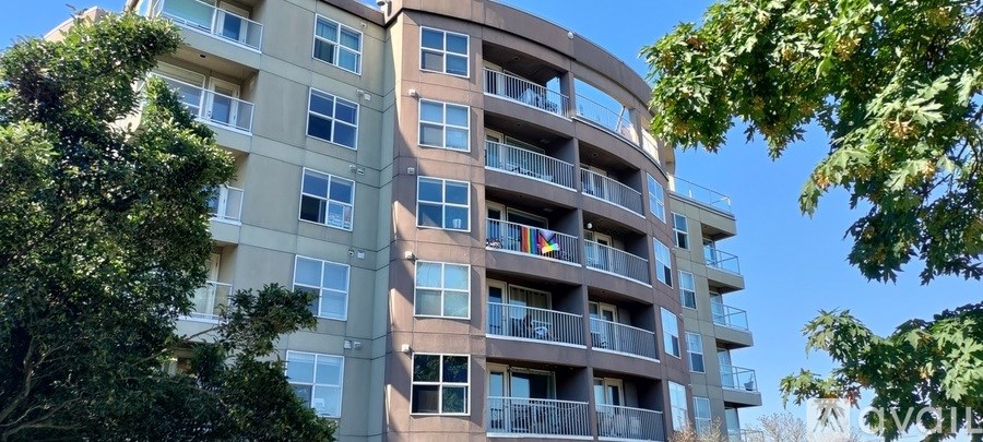 A tall apartment building with balconies and flags hanging from the balconies.