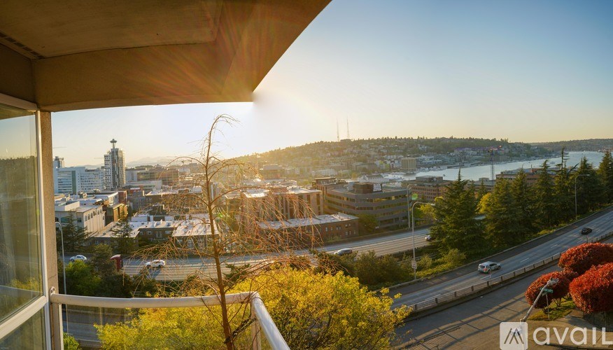 A view from a balcony overlooking a cityscape with buildings, trees, and a highway.