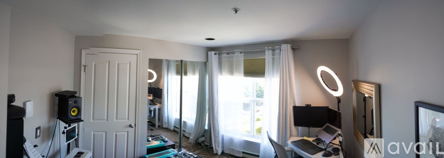 A room with a bed, a desk, a chair, a speaker, and a lamp.