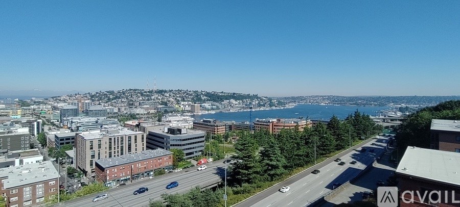 A cityscape with a clear blue sky and a body of water in the distance.