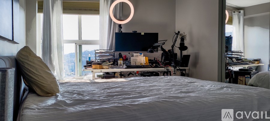 A bedroom with a large bed and a desk with a computer and other items on it.