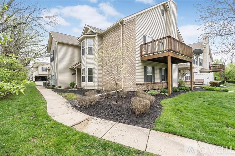 A house with a well-maintained lawn and a small tree in the front yard.