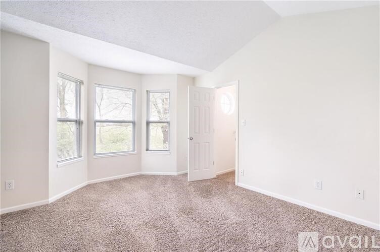 A room with a carpeted floor and a door leading to another room.