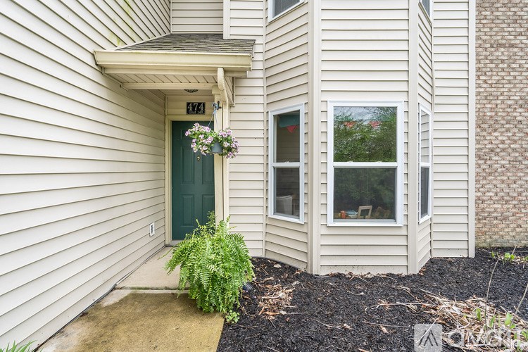 A house with a green door and a window with a view of trees.