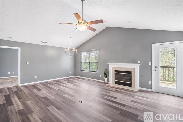 A spacious living room with a fireplace and a ceiling fan.