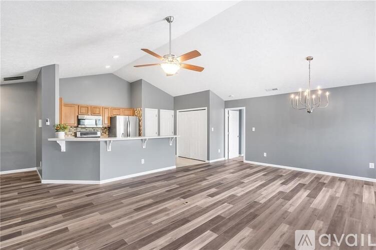 A spacious living room with a ceiling fan and hardwood flooring.