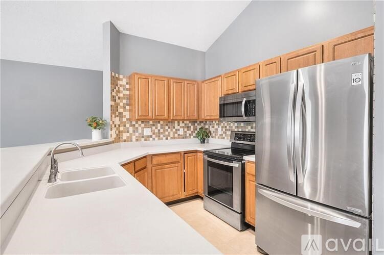 A kitchen with wooden cabinets and a stainless steel refrigerator.