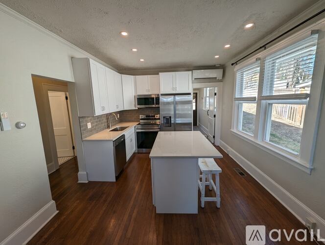A kitchen with white cabinets and a wooden floor.