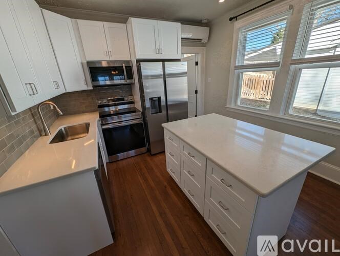 A kitchen with white cabinets and a wooden floor.