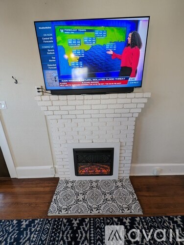 A woman in a red sweater is on a TV screen showing a weather forecast.