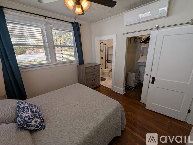 A bedroom with a bed, a ceiling fan, and a door leading to a bathroom.