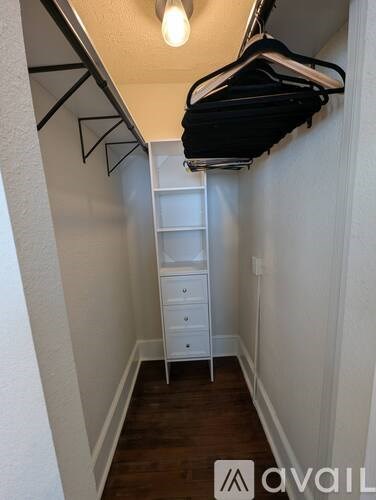 A small white closet with a hanging rod and a white dresser.
