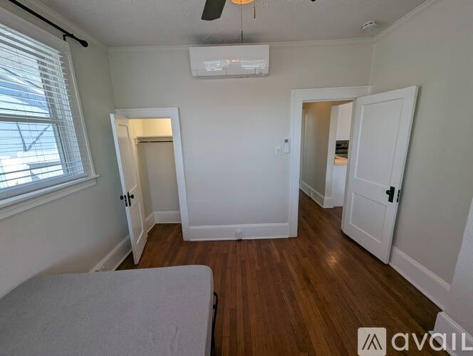 A bedroom with a bed, a window with blinds, and a ceiling fan.