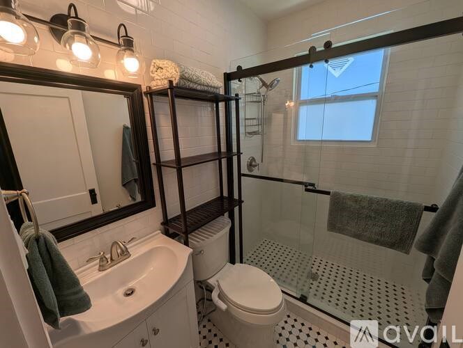 A bathroom with a white toilet, sink, and shower.