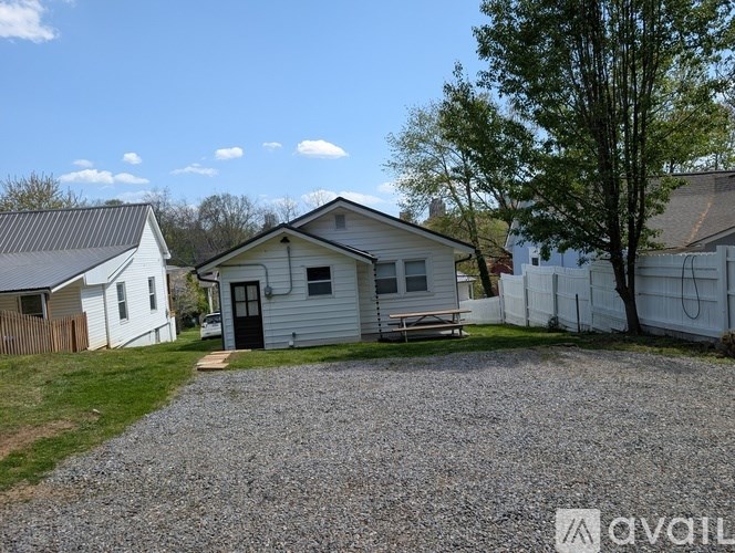 A gravel driveway leads to a white house with a black door.