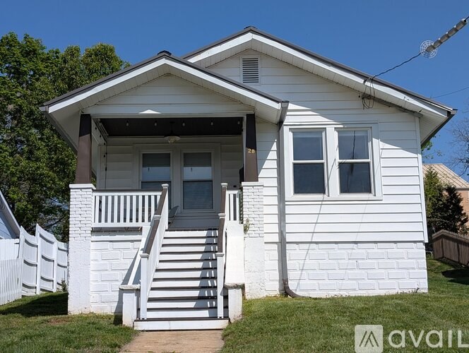 A white house with a porch and a staircase leading to the front door.