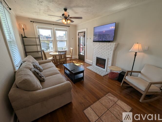 A living room with a white fireplace and a television mounted above it.