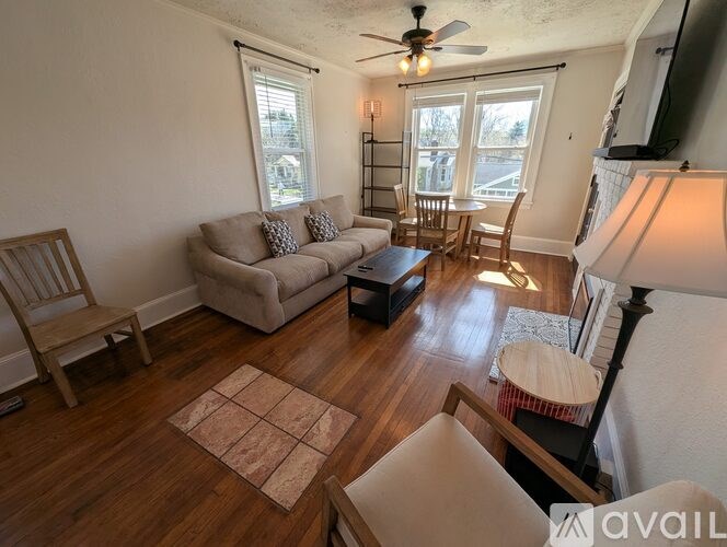 A living room with a beige couch, a wooden chair, a brown rug, and a ceiling fan.