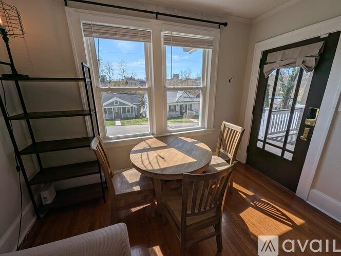 A room with a table and chairs in front of a window.