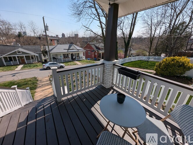 A deck with a table and chairs overlooking a residential street.