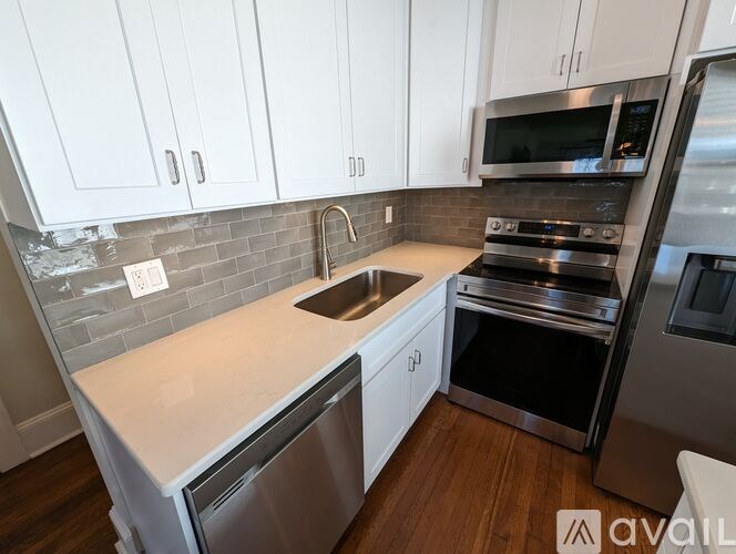 A kitchen with white cabinets and a stainless steel refrigerator.