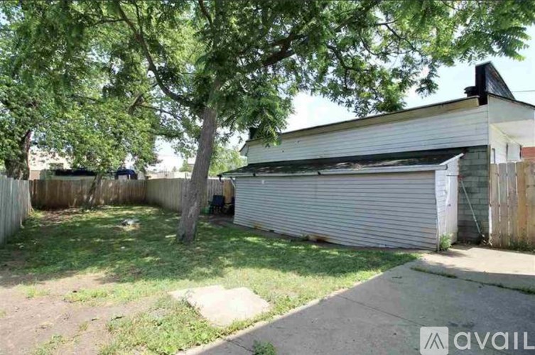 A backyard with a tree and a garage door.