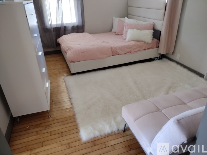 A bedroom with a pink bed and a white rug.