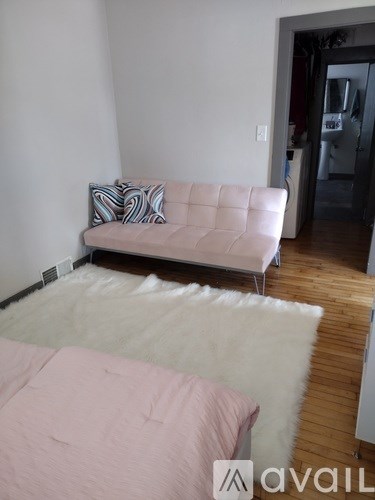 A living room with a pink couch and a white rug.