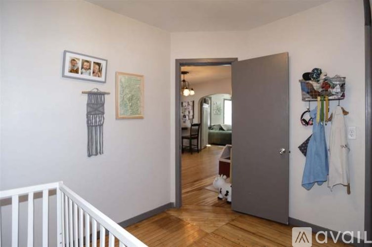 A room with a white crib and a wall with pictures and a coat rack.