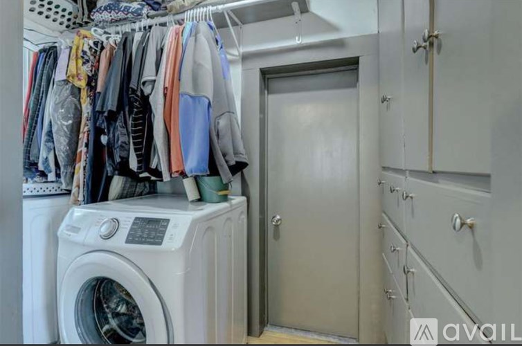 A laundry room with a washing machine and clothes hanging up.