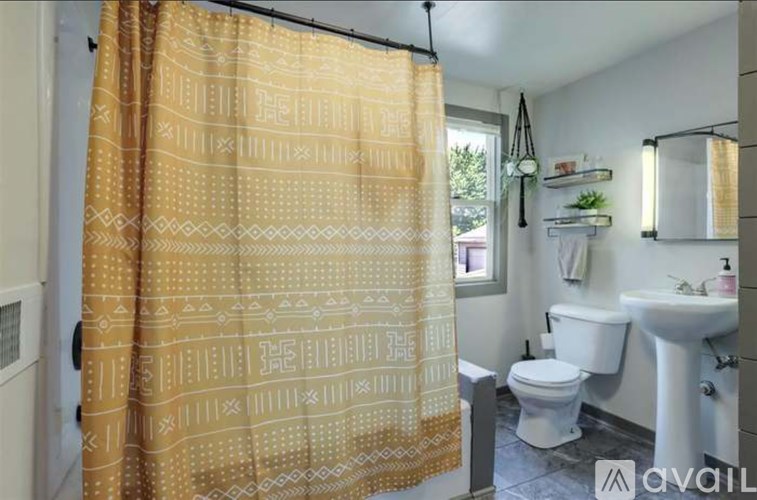 A bathroom with a yellow shower curtain and white fixtures.