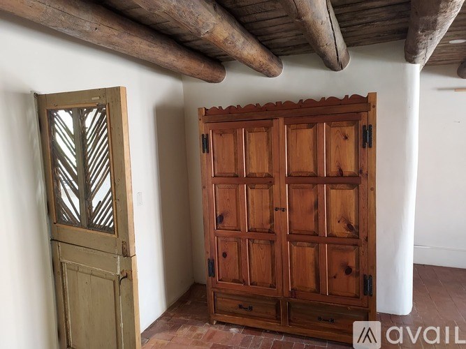 A wooden door with a window is on the left and a wooden wardrobe on the right.