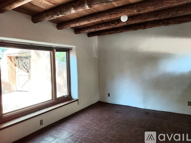 A room with a window and wooden beams on the ceiling.