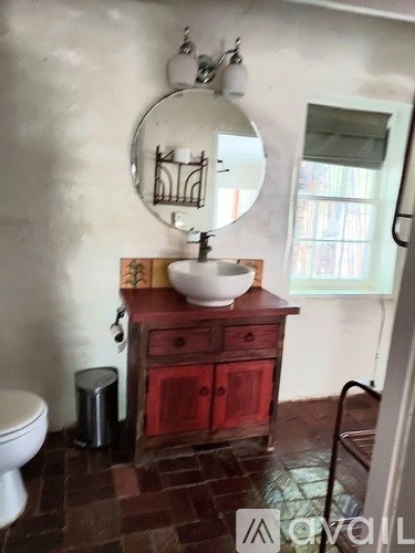 A bathroom with a red vanity and a round mirror.