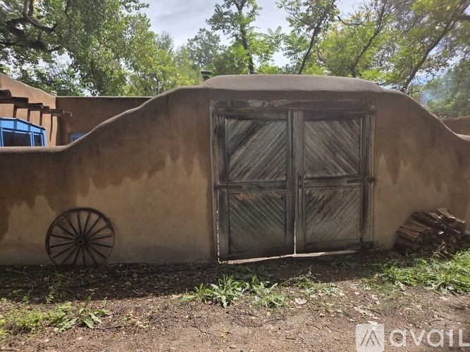 A brown adobe building with a wooden door and a wooden wheel.