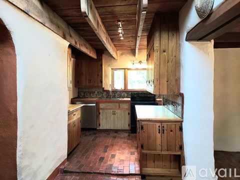 A kitchen with wooden cabinets and a brick floor.