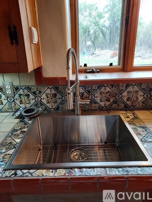 A kitchen sink with a chrome faucet and a tiled counter.