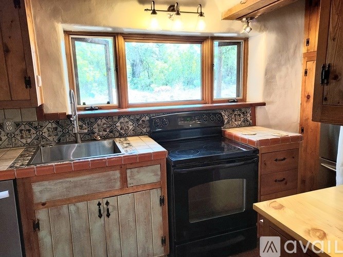 A kitchen with a black stove top oven and a sink with a metal faucet.