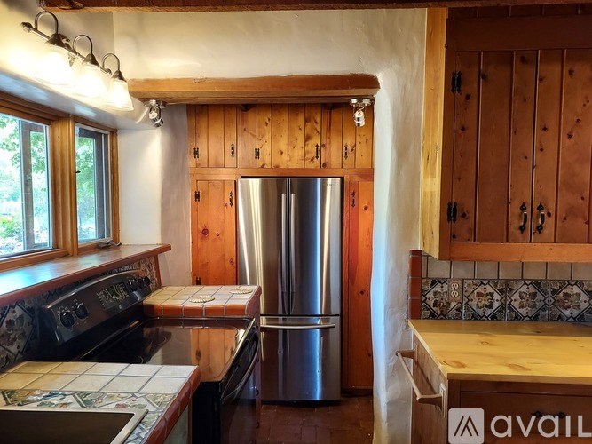 A kitchen with wooden cabinets and a stainless steel refrigerator.