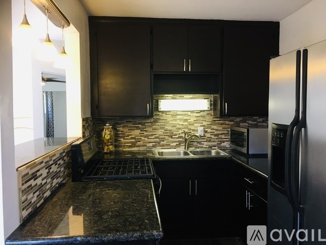 A kitchen with black cabinets and a granite countertop.