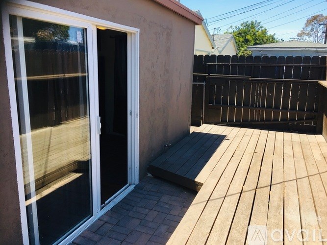 A patio with a sliding glass door and a wooden deck.
