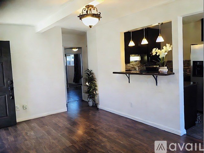 A room with a wooden floor and a wall-mounted shelf with a vase of flowers on it.