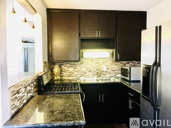 A kitchen with a black granite countertop and a refrigerator.