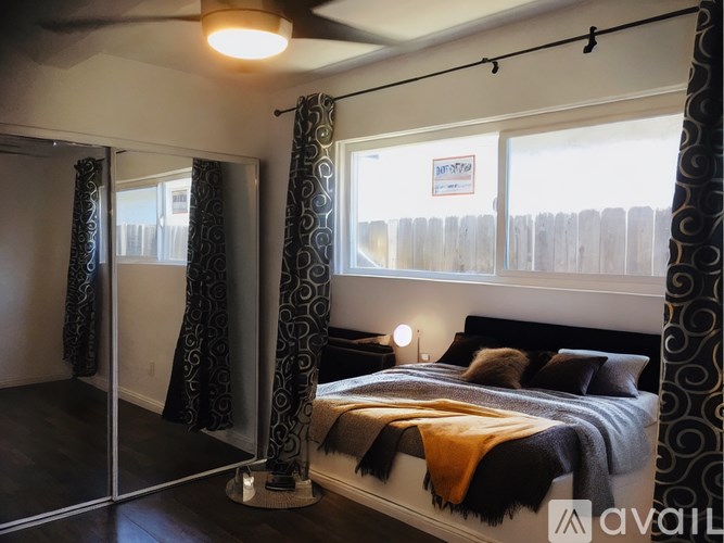 A bedroom with a bed, curtains, and a mirror.